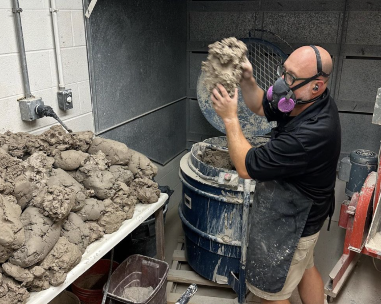 Ben Huber putting the leftover clay into a machine to reuse it. Photo Provided. 